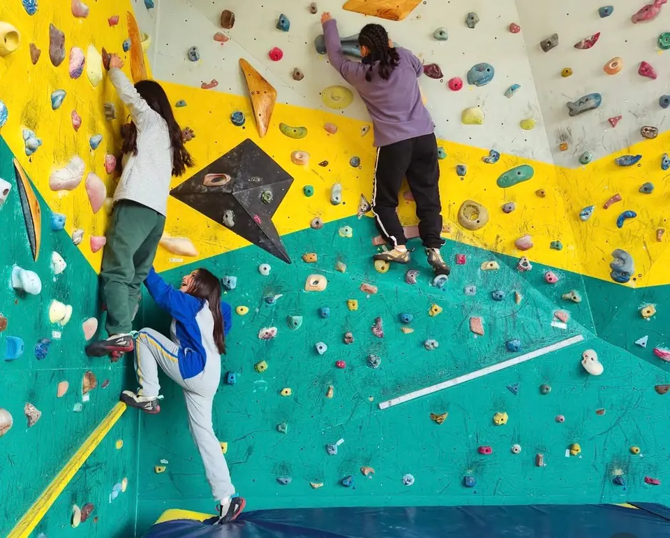 Persona escalando el muro de Andes Extremo con arnés y casco